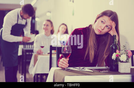 Femme élégante en colère s'attend à ce que l'homme pour le dîner dans le restaurant de luxe intérieur. Banque D'Images