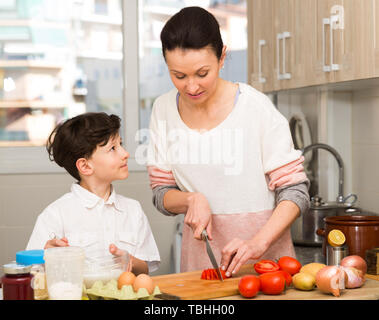 Femme positive et son fils préadolescent de préparer des aliments et drôle à parler cuisine intérieur confortable Banque D'Images