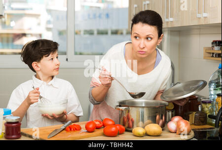 Femme positive et son fils préadolescent de préparer des aliments et drôle à parler cuisine intérieur confortable Banque D'Images