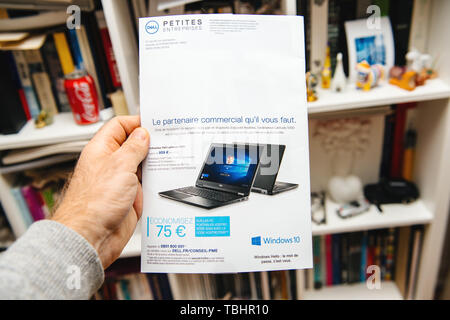 Paris, France - Apr 16, 2019 : Man hand holding Ordinateurs Dell publicité dépliant distribué aux petites entreprises Les petites entreprises avec des nouveaux ordinateurs portables Dell Latitude 5590 contexte de la bibliothèque Banque D'Images