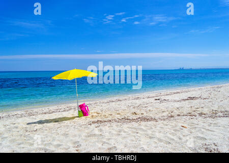 Parasol jaune sur une plage de sable blanc en Sardaigne, Italie Banque D'Images