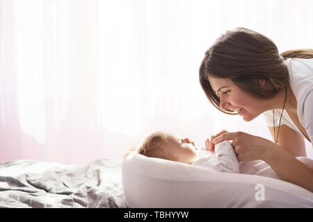 Mère et son fils nouveau-né était étendue sur le lit dans les rayons du soleil Banque D'Images