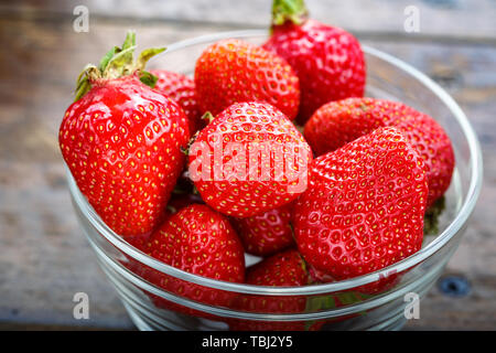 Fraises fraîches biologiques dans une plaque de verre. été la récolte sur un fond en bois brun Banque D'Images