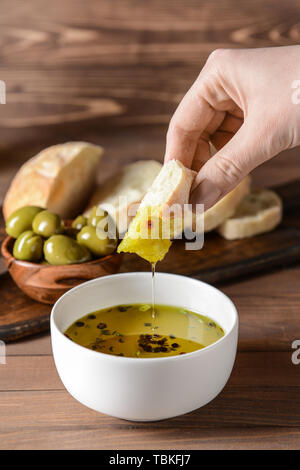 Femme trempant du pain frais dans l'huile d'olive savoureuse dans un bol Banque D'Images