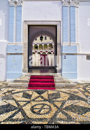 L'Église chrétienne orthodoxe de la Vierge Marie à l'ile de Tinos, Grèce, noir et blanc cailloux marbre, entrée principale, escalier avec tapis rouge. Banque D'Images