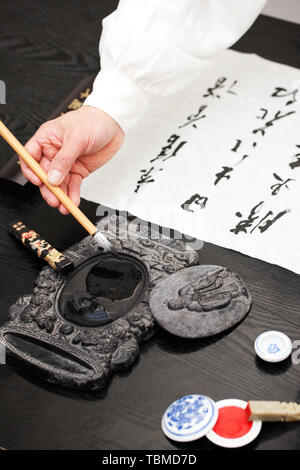 Un vieil homme pratiquant la calligraphie Banque D'Images