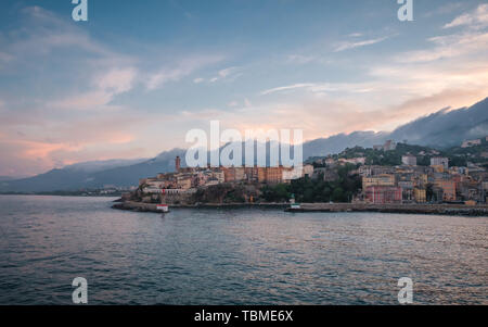 Le crépuscule tombant sur le port et la vieille ville de Bastia dans le nord de la Corse avec cliud couverts montagnes au loin Banque D'Images