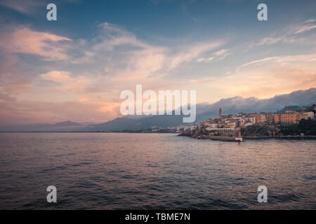 Le crépuscule tombant sur le port et la vieille ville de Bastia dans le nord de la Corse avec cliud couverts montagnes au loin Banque D'Images