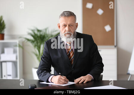 Mature businessman sitting at table in office Banque D'Images