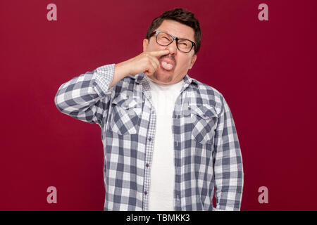 Portrait de funny crazy handsome middle aged man in casual chemise à carreaux et des lunettes, le forage permanent son nez et langue à l'intérieur. Banque D'Images