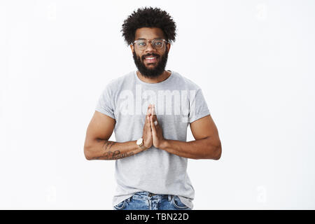 Namaste amis. Friendly-heureuse et pacifique à la maturité de l'Amérique africaine barbu avec les cheveux bouclés et les tatouages dans les verres smiling at camera gree Banque D'Images