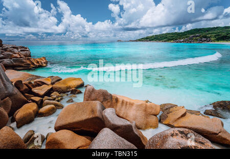 Vague en rouleau et de superbes formations granitiques sur la belle île tropicale avec des nuages blancs de La Digue, Seychelles Banque D'Images