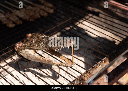 Close up de tête de crocodile grillés sur le charbon cuisinière dans la rue du marché. Concept de l'alimentation et la cuisine exotique. Banque D'Images