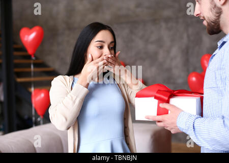 Young woman receiving présente de son petit ami à la maison Banque D'Images