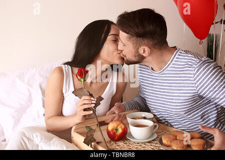 Jeune femme qui reçoit un petit déjeuner au lit de son mari bien-aimé Banque D'Images