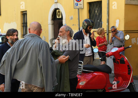 Rassemblement d'hommes parlant italien et le tabagisme dans les rues de Brescia Italie Banque D'Images