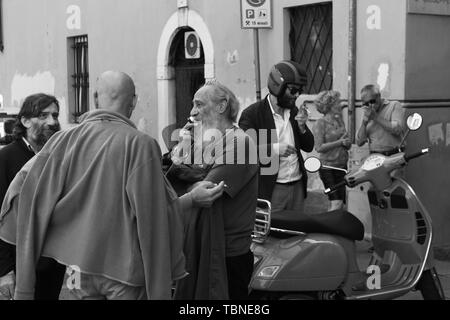 Rassemblement d'hommes parlant italien et le tabagisme dans les rues de Brescia Italie Banque D'Images