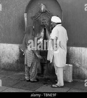 Asian couple remplir bouteille d'eau en plastique d'une fontaine d'eau publique à Brescia Italie Banque D'Images