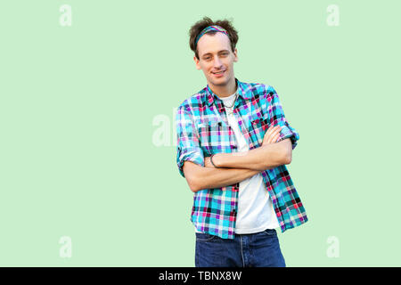 Portrait de Professionnels satisfaits jeune homme en chemise à carreaux bleu et debout, serre-tête à la caméra à croseed avec armes et sourire à pleines dents indo. Banque D'Images