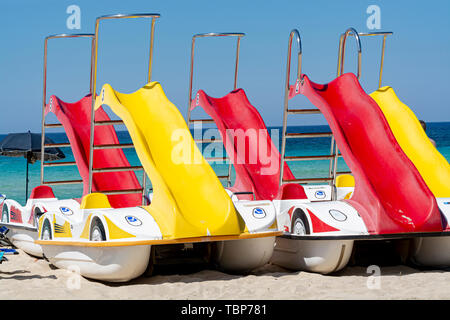 Pédalos colorés avec des toboggans à louer sur la plage de sable avec de l'eau de mer bleue Banque D'Images