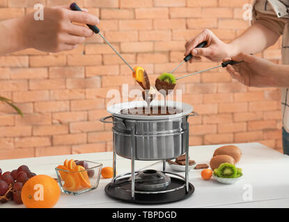 Les femmes trempant les fruits dans la fondue au chocolat Banque D'Images