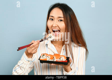 Asian woman eating sushi sur un fond de couleur Banque D'Images