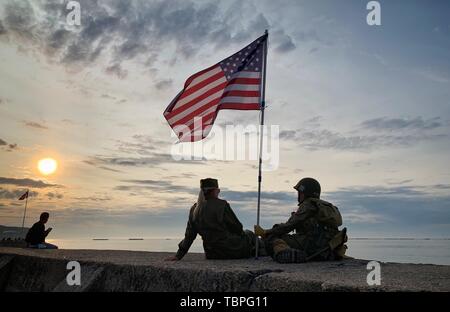 La France. 02 juin 2019, la France (France), Arromanches-les-Bains : une mère danoise et son fils s'asseoir dans l'uniforme des soldats américains historique en face de la demeure de l'ancien port sur Gold Beach. Après le débarquement des troupes alliées l'un des deux ports artificiels Mulberry (B) a été construit au large de la côte de Arromanches-les-Bains, à travers lequel des troupes et du matériel ont été ramenées à terre. 06.06.2019 est le 75e anniversaire de le débarquement des troupes alliées en Normandie. Photo : Kay Nietfeld/dpa Banque D'Images