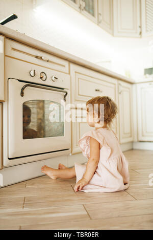 Femme enfant assis sur le plancher à la four Banque D'Images