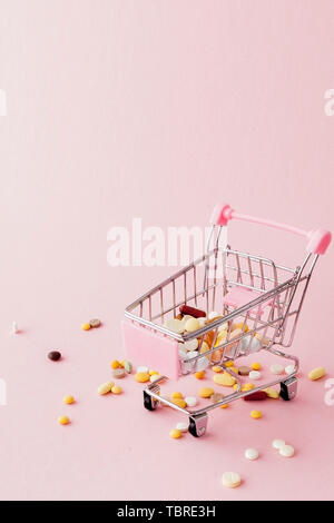 Panier du supermarché plein de pilules et drogues sur un fond rose. Les achats de médicaments, l'achat sur Internet. Télévision Banque D'Images