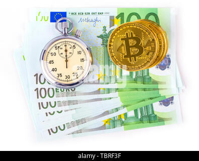 Les Bitcoins sur une pile d'une centaine d'euros et d'une lampe réveil sur un fond blanc. Banque D'Images