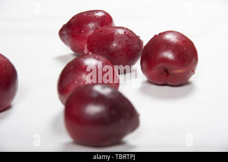 Prune rouge posé nonchalamment sur fond blanc Banque D'Images