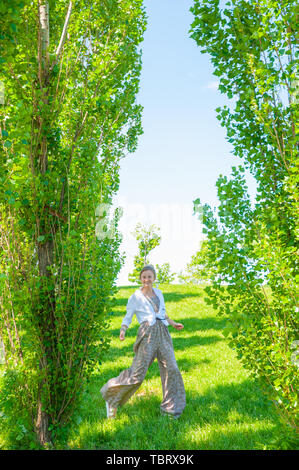 Beau style Boho femme marche sur l'herbe et profiter de l'heure d'été au parc. Moment heureux. Banque D'Images