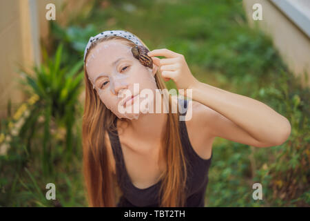 Une jeune femme fait un masque de visage avec le mucus de l'escargot. Escargot de ramper sur un masque de visage Banque D'Images