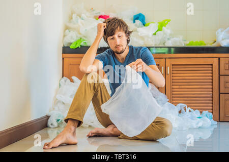 L'homme utilisé trop de sacs en plastique qu'ils ont rempli l'ensemble de la cuisine. Concept zéro déchet. Le concept de la Journée mondiale de l'environnement Banque D'Images