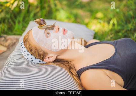 Jeune femme fait un masque de visage avec le mucus de l'escargot. Escargot de ramper sur un masque de visage Banque D'Images