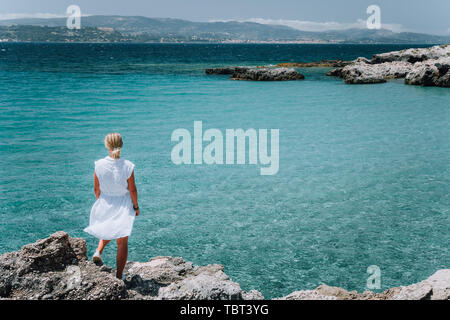 Jung femmes adultes en robe blanche sur les vacances d'été en face de la côte de la mer paysage de petite plage avec eau cristalline de l'eau. Grèce, Céphalonie Banque D'Images