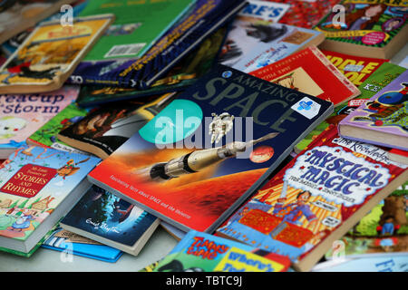 Pile de livres pour enfants en vente sur un étal de bienfaisance dans la région de Sussex, UK. Banque D'Images