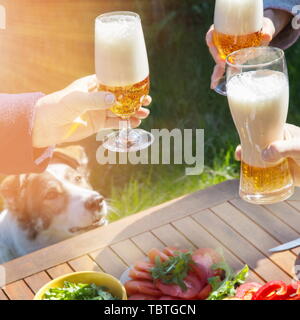 Famille de différents âges gens célébrer joyeusement en plein air avec des verres de bière proclamer toast. Banque D'Images