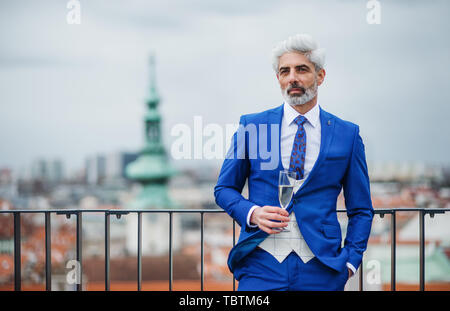 A mature woman with glass sur une partie en plein air sur la terrasse du toit en ville. Banque D'Images