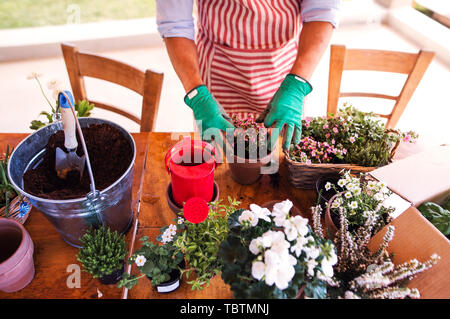 Un portrait de jeune homme jardinier dehors à la maison, planter des fleurs. Banque D'Images