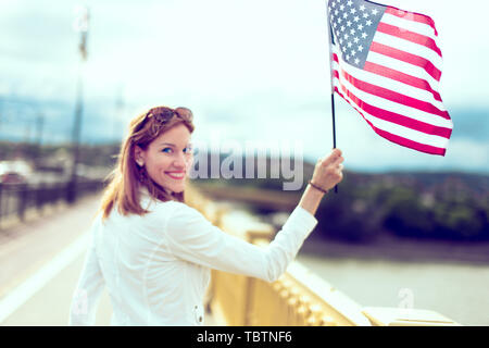 Jeune femme tenant un drapeau USA en ville, selective Focus, profondeur de champ Banque D'Images