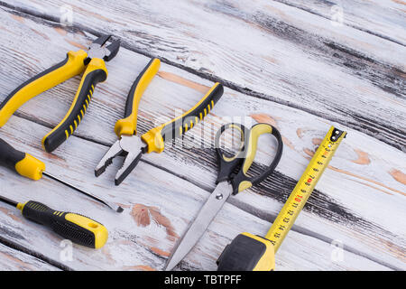 Ensemble d'outils sur fond de bois. Pinces, tournevis, ciseaux et ruban à mesurer. Outils pour le constructeur ou d'un plombier. Banque D'Images