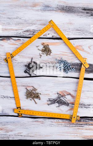 Mètre pliant en forme de maison sur fond de bois. La composition avec builder règle, vis et clous. Concept de construction. Banque D'Images