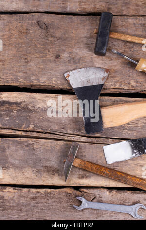 Divers outils de travail sur des planches en arrière-plan. Marteau, tournevis, hache, spatule et clés sur planches de bois fendu. Banque D'Images