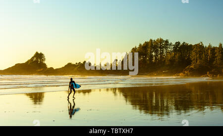 Un surfeur marche le long d'une plage sur l'île de Vancouver, en Colombie-Britannique, au Canada Banque D'Images