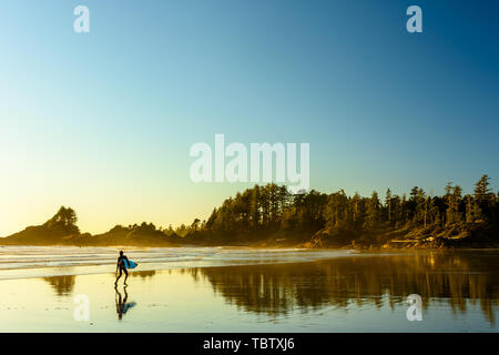 Un surfeur marche le long d'une plage sur l'île de Vancouver, en Colombie-Britannique, au Canada Banque D'Images