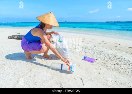 Femme la collecte des bouteilles en plastique sur la magnifique plage tropicale, mer turquoise, journée ensoleillée, recyclage déchets concept, la protection de l'environnement. Banque D'Images