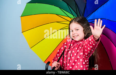 Petite fille en imperméable. automne fashion hipster joyeux. enfant dans l'humeur positive. protection contre la pluie. Arc-en-ciel. Heureux petite fille avec parapluie colorés. Belle désinvolture. Banque D'Images