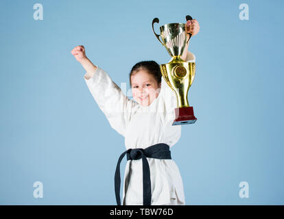 Petite fille avec champion cup. arts martiaux. gagnant petite fille dans gi sportswear. pratiquer le Kung Fu.. de la petite enfance et de l'activité de l'énergie. pour les enfants. sport succès en combat singulier. Beauté sportive. Banque D'Images