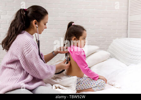 Main de doctor with stethoscope enfant écoute de retour. Pédiatre vérifie stéthoscope souffle une petite fille Banque D'Images